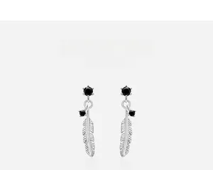 Macro shot of 925 sterling silver feather earrings with black gemstones and natural textures