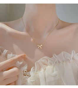 Close-up of elegant gold bow pendant necklace with sparkling zircons on model neck