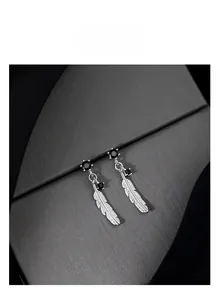 Detail view of 925 silver feather earrings featuring inlaid black gemstone accents