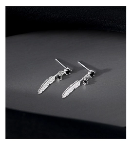 Macro detail of 925 silver feather earrings featuring black gemstones and retro texture