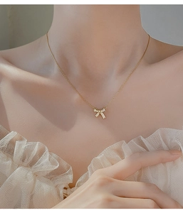 Macro detail of a 925 silver bow necklace with pavé zircon stones on a gold-plated chain