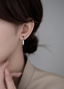 Close-up of 925 sterling silver feather earrings with black gemstones on a model