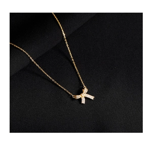 Detailed close-up of a gold bow pendant necklace featuring sparkling micro-pave stones