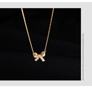 Close-up of golden 925 silver bow necklace featuring sparkling pavé zircon stones