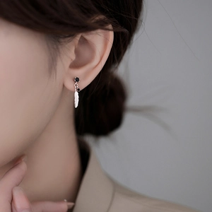 Elegant 925 sterling silver feather earrings with black zircon stones worn by a model