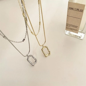 Detail view of double-layered gold and silver necklaces with hollow rectangular pendants