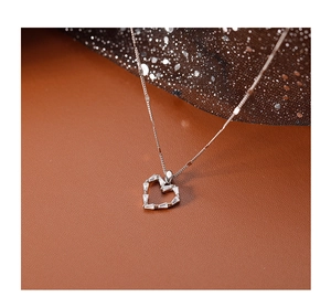 Gros plan du collier coeur évidé en argent 925 avec zircons cubiques sur tissu brillant