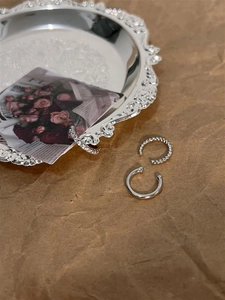 Detailed close-up of three distinct silver-tone ear cuffs on a vintage decorative tray