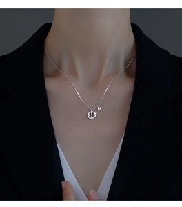 Détail du pendentif lettre H en argent 925 serti de cristaux sur le cou du mannequin
