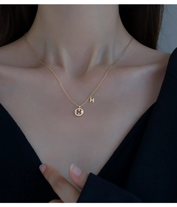 Gros plan d'un collier en argent 925 doré avec pendentif lettre H et zircons étincelants