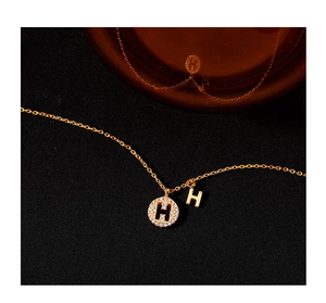 Gros plan du collier en argent 925 doré avec pendentif rond lettre H serti de diamants