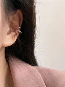 Detail shot of three-piece gold cuff earrings with cubic zirconia on a model ear