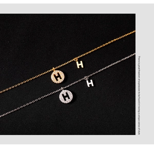 Détail de colliers avec pendentif lettre H en or et argent sertis de zircons cubiques
