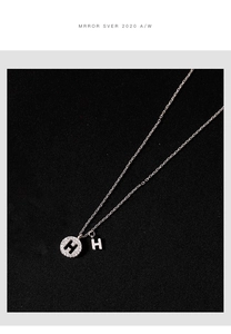Détail macro du collier en argent 925 avec deux pendentifs lettre H et zircons blancs étincelants
