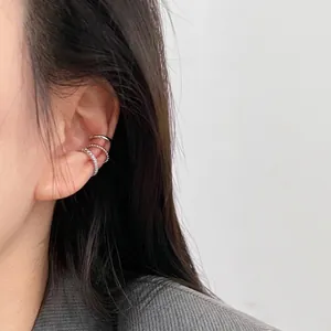 Three-piece silver ear cuff set with rhinestones worn by a model in a close-up view