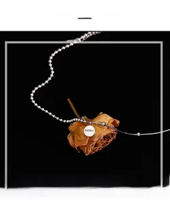 Detail of 925 silver lucky necklace with asymmetric beads and snake chain on black fabric