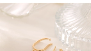 Detailaufnahme der goldfarbenen Ohrmanschette mit eleganten U-Kurven und feiner Kette
