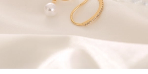 Detailaufnahme einer goldfarbenen Earcuff mit Zirkonia-Steinen und weißem Perlenanhänger