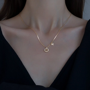Élégant collier avec pendentif lettre H en argent 925 porté sur un col en V noir chic