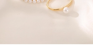 Nahaufnahme eines goldenen Perlenrings auf beige Seide zeigt Textur und Glanz des Schmucks
