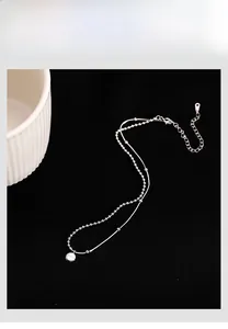 Detail view of double-layer 925 silver necklace with Lucky pendant on black background