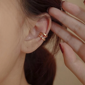 Detailed macro view of honeycomb gold ear cuffs featuring sparkling zircon accents on the ear