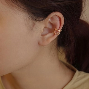 Detail shot of golden honeycomb double-ring ear cuff worn on an ear without piercing