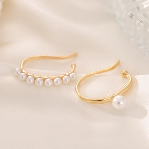 Elegantes Gold-Perlen-Ohrklemmen-Set im minimalistischen Stil auf weißem Satinstoff