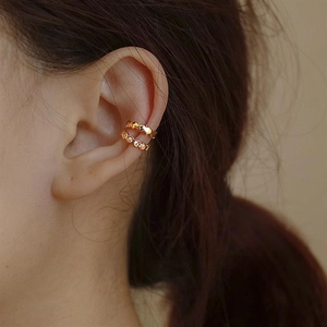 Close-up of golden double-layered honeycomb ear cuff with shimmering zircon accents