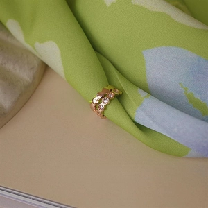 Macro shot of rose gold honeycomb ear cuff with zircon inlay on a silk background