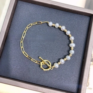Elegant pearl bracelet with gold chain and OT toggle clasp on a dark gray velvet display