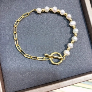 Elegant pearl and golden paperclip chain bracelet with toggle clasp on dark jewelry box
