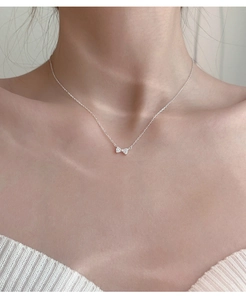 Fijne zilveren strik hanger ketting met zirkonia stenen op een vrouwelijk model