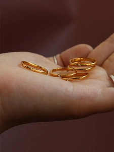 Detail of minimalist gold geometric rings with tiny diamonds held in palm of hand