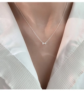 Détail d'un pendentif nœud en argent avec pierres scintillantes sur une fine chaîne