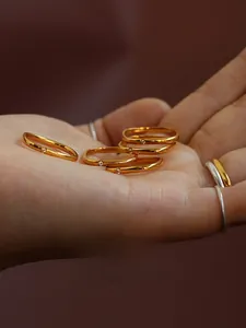 Close-up of gold geometric rings with diamond accents held on a hand against dark background