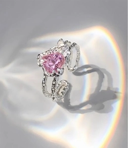 Macro view of pink heart-shaped crystal ring with silver molten lava texture band