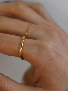Close-up of minimalist thin gold ring with a single small diamond on a model's finger