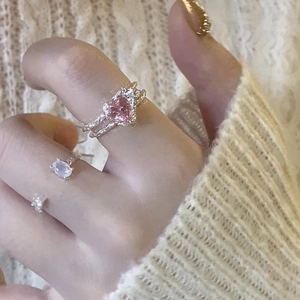 Detailed close-up of a silver pink heart-shaped crystal ring worn on hand with sweater