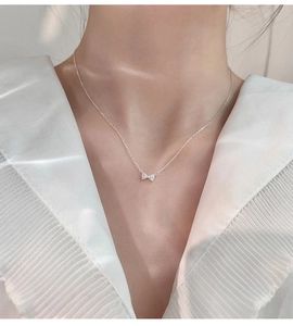 Détail d'un collier nœud argenté orné de zircones sur une chaîne minimaliste élégante