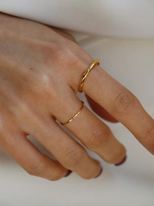 Close-up of gold square rings set with diamond and handmade hammered texture on hand