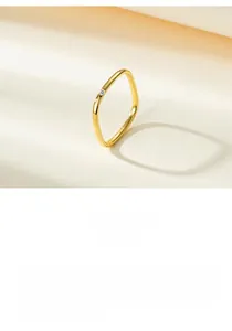 Detail of minimalist wavy gold ring with micro-set round clear gemstone in a soft light