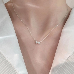 Collier minimaliste en argent avec pendentif nœud porté avec une chemise blanche