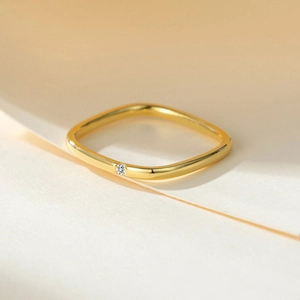 Elegant gold square ring with a sparkling center diamond on warm white background