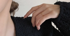 Gros plan d'une bague dorée avec trois diamants verticaux sur un modèle en tricot noir