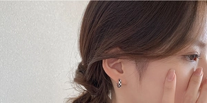Gros plan de créoles en damier noir et blanc portées par un mannequin sur l'oreille