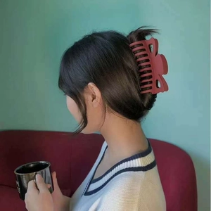 Matte clay red bow hair claw clip securing thick hair for an elegant updo hairstyle