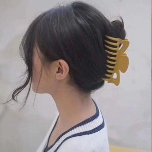 Side view of a model wearing a large matte yellow shark hair claw clip in a hair bun