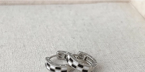 Vue détaillée des créoles émaillées à damier noir et blanc avec une base en métal argenté