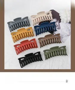 Flat lay of large matte hair claws in eight assorted colors on a neutral textured background